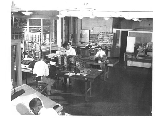 Black and white image of Remingrton Rand Laboratory for Advanced Research in Norwalk CT. Prototype/engineering model leading to Model 409. Left Charles Nickols, Gordon Chamberlain, Al Greenfield, unknown at drawing board.